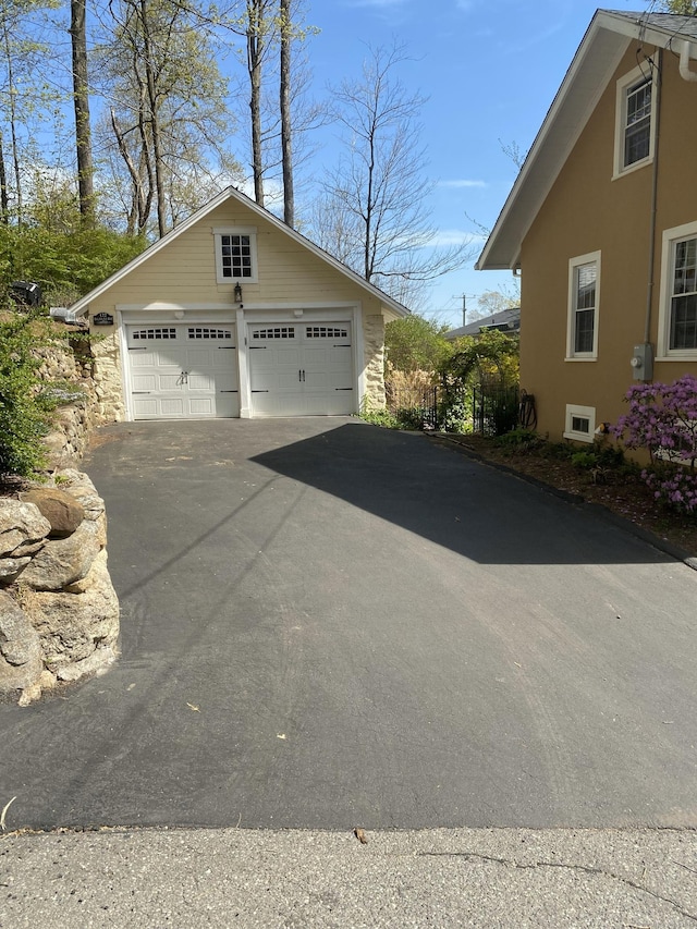 view of side of home with stucco siding, an outbuilding, stone siding, and a detached garage