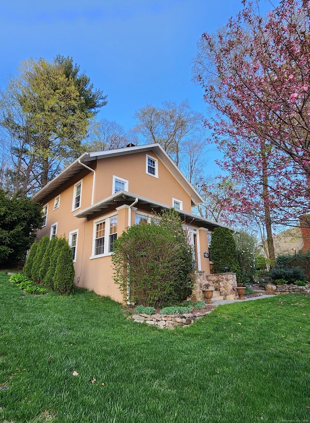 view of property exterior with stucco siding and a yard