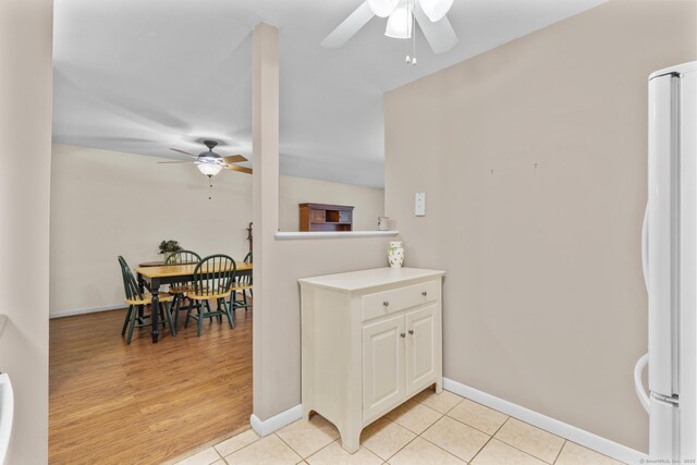 kitchen featuring ceiling fan, light countertops, light tile patterned floors, baseboards, and freestanding refrigerator