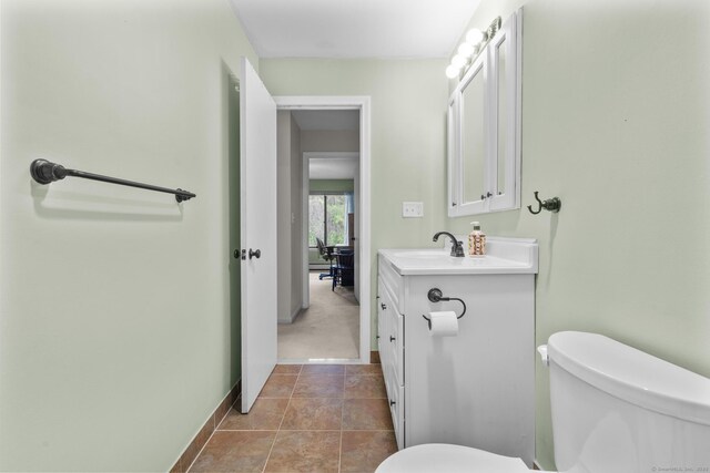 half bathroom featuring baseboards, toilet, and vanity