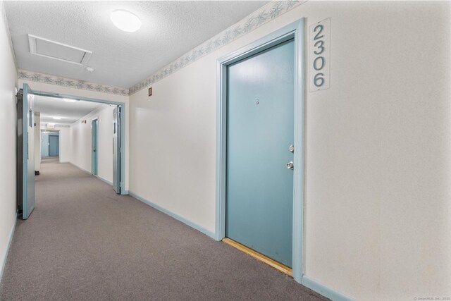 hallway featuring baseboards, carpet, and a textured ceiling