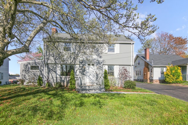 colonial-style house featuring a chimney and a front yard