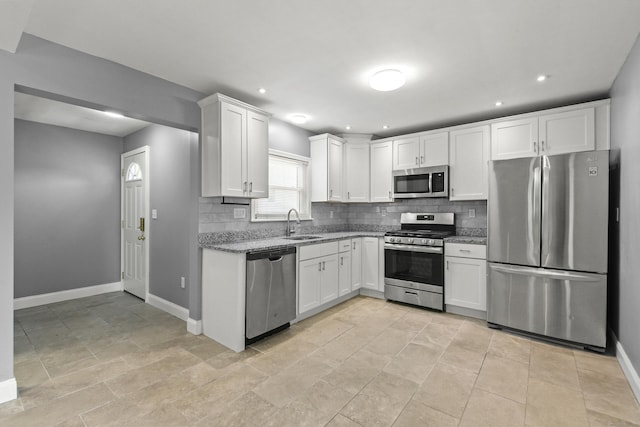 kitchen with baseboards, white cabinetry, appliances with stainless steel finishes, and tasteful backsplash