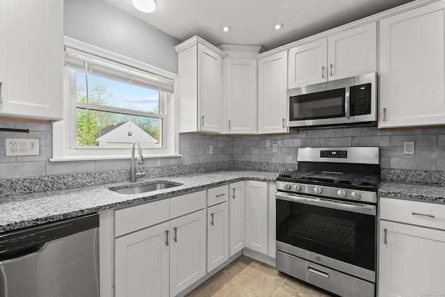 kitchen with white cabinets, stainless steel appliances, a sink, and tasteful backsplash