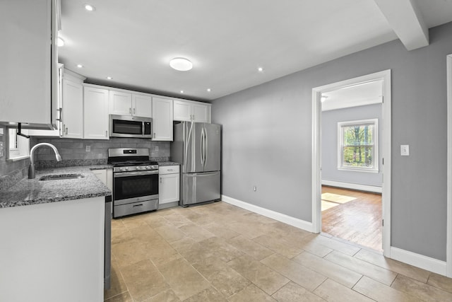 kitchen featuring a sink, stainless steel appliances, white cabinetry, a baseboard radiator, and backsplash
