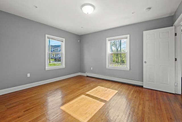 unfurnished bedroom with baseboards, a baseboard heating unit, and hardwood / wood-style floors