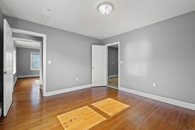 unfurnished bedroom with baseboards, a baseboard heating unit, and hardwood / wood-style floors