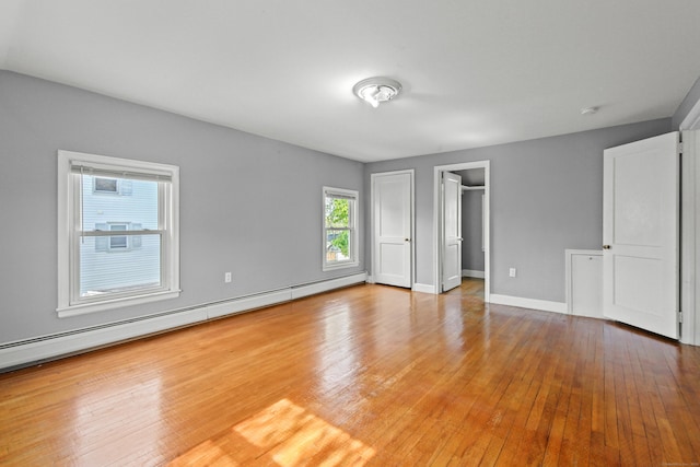 unfurnished bedroom with baseboards, baseboard heating, and hardwood / wood-style flooring