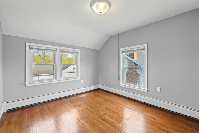 additional living space with wood-type flooring, baseboards, a baseboard heating unit, and lofted ceiling