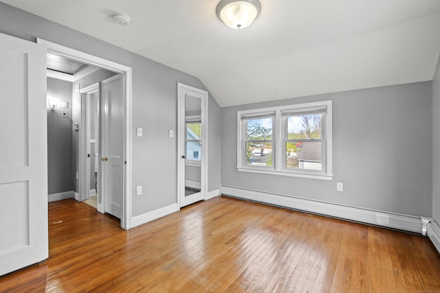 unfurnished bedroom featuring baseboards, vaulted ceiling, baseboard heating, and hardwood / wood-style floors