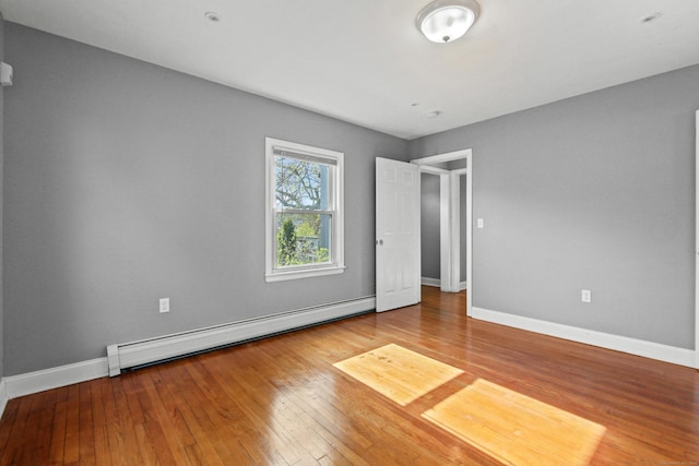 empty room with baseboards, a baseboard heating unit, and hardwood / wood-style flooring