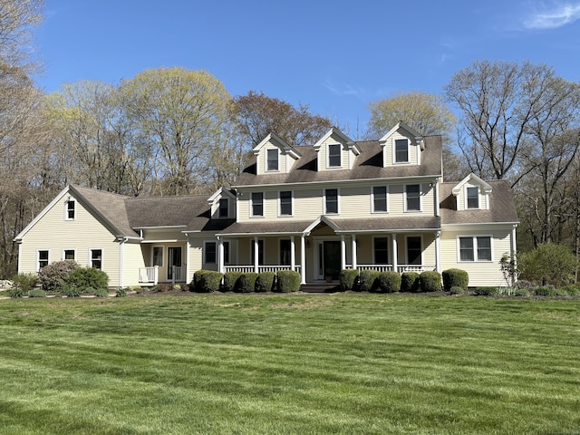 view of front of home featuring covered porch, a shingled roof, and a front lawn