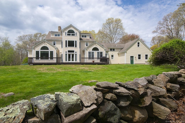 rear view of property featuring a yard, a deck, french doors, and a chimney