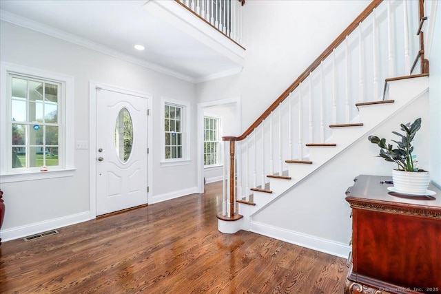 foyer with visible vents, crown molding, stairs, wood finished floors, and baseboards