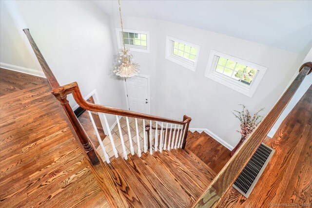 stairs with baseboards, wood finished floors, and visible vents