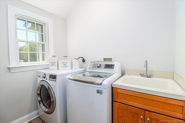 clothes washing area featuring washing machine and clothes dryer, baseboards, a sink, and cabinet space