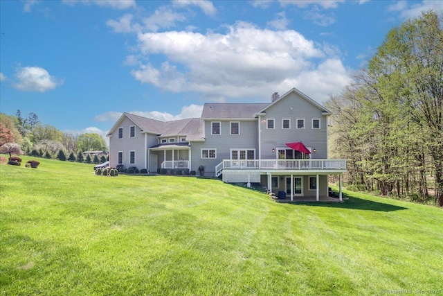 back of property with a chimney, a yard, and a deck