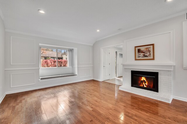 unfurnished living room featuring crown molding, a brick fireplace, wood finished floors, baseboards, and recessed lighting
