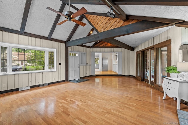 unfurnished living room featuring wood finished floors, a ceiling fan, and wood walls