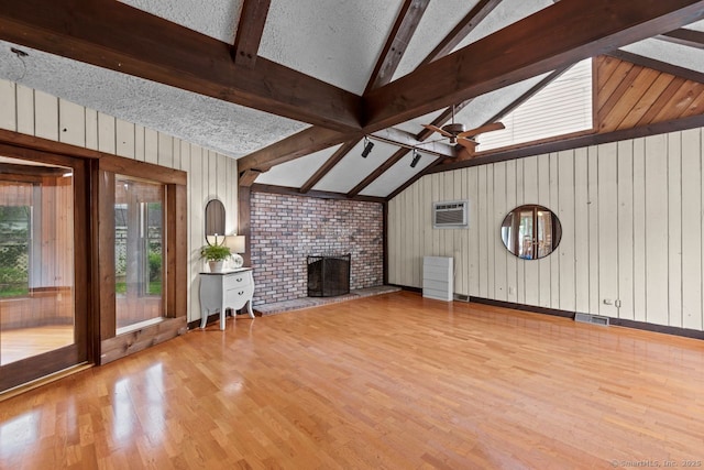 unfurnished living room featuring wood finished floors, wood walls, a ceiling fan, a wall mounted air conditioner, and a brick fireplace