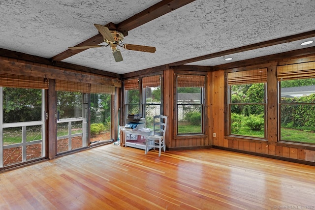 unfurnished sunroom with wood finished floors, wood walls, and beam ceiling