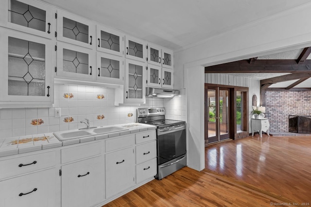 kitchen with stainless steel electric stove, a sink, tile counters, under cabinet range hood, and light wood-style flooring