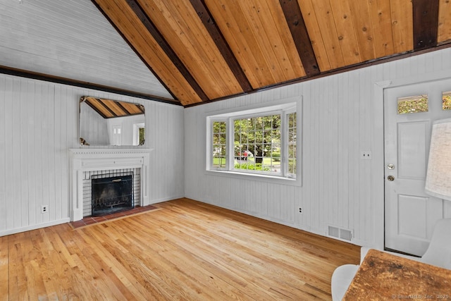 unfurnished living room with wood-type flooring, a brick fireplace, wood walls, and wooden ceiling