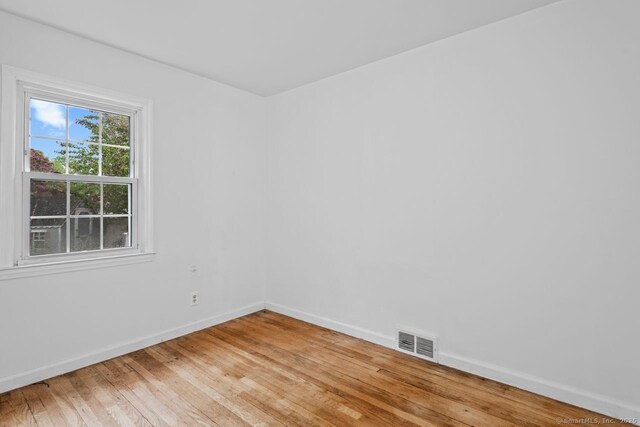 spare room featuring light wood-type flooring and baseboards