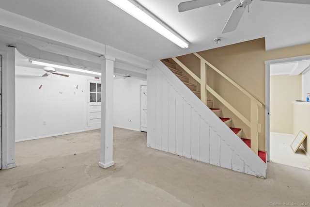 below grade area with ceiling fan and stairs
