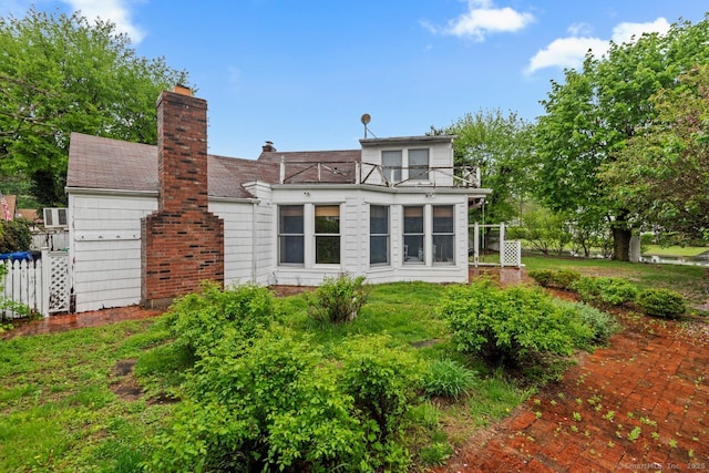 back of property featuring a balcony and a chimney