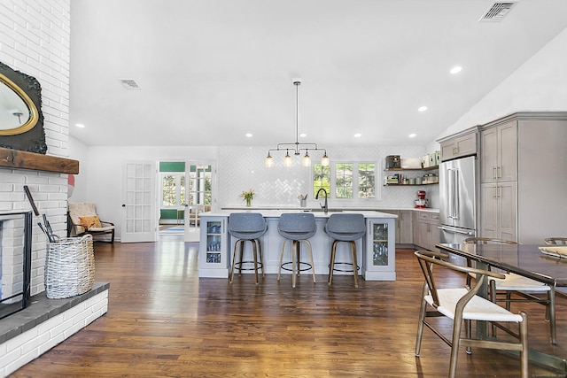 kitchen featuring visible vents, open shelves, high end refrigerator, and gray cabinetry