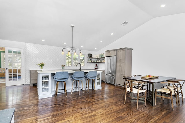 kitchen featuring visible vents, open shelves, lofted ceiling, high quality fridge, and gray cabinetry