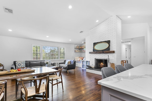 living area featuring visible vents, dark wood-style flooring, a brick fireplace, and vaulted ceiling