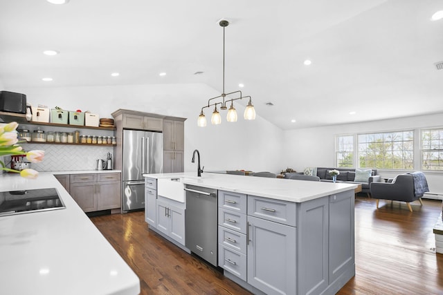 kitchen featuring vaulted ceiling, gray cabinetry, a sink, open floor plan, and stainless steel appliances