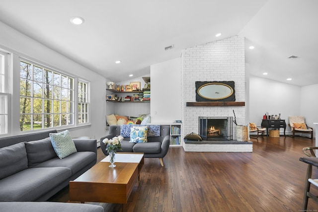 living area featuring visible vents, vaulted ceiling, a brick fireplace, wood finished floors, and recessed lighting