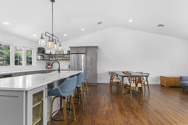 kitchen with decorative backsplash, visible vents, open shelves, gray cabinetry, and lofted ceiling