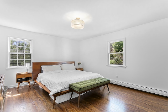 bedroom featuring baseboards, multiple windows, baseboard heating, and dark wood-type flooring