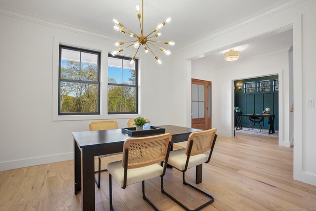 dining space with light wood-style floors, baseboards, ornamental molding, and a notable chandelier
