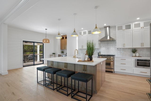 kitchen featuring decorative backsplash, wall chimney range hood, a kitchen bar, light countertops, and high end range