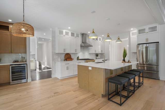 kitchen featuring a sink, beverage cooler, wall chimney exhaust hood, tasteful backsplash, and high end refrigerator