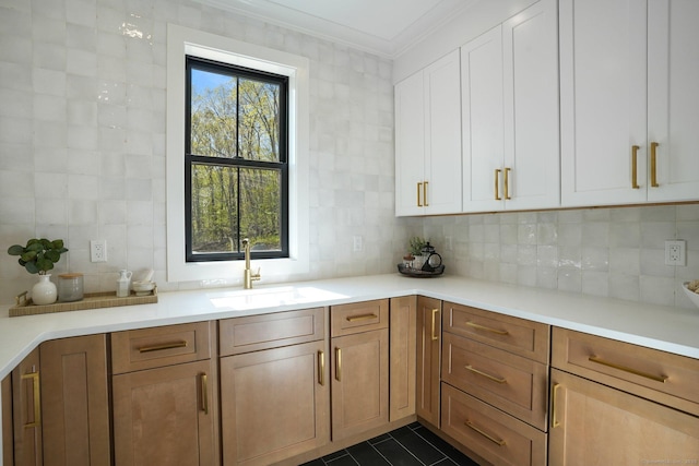 kitchen with backsplash, crown molding, a sink, light countertops, and white cabinets