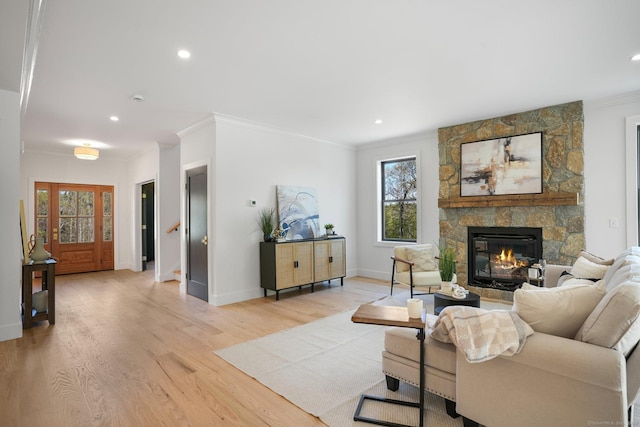 living area featuring crown molding, a fireplace, light wood finished floors, and a healthy amount of sunlight