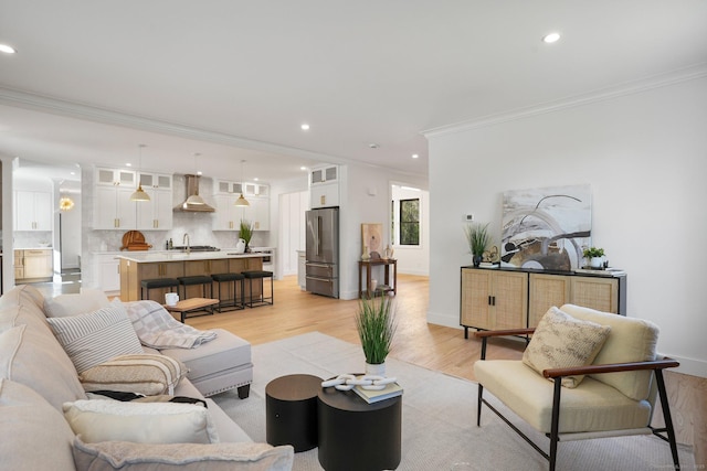 living room with crown molding, recessed lighting, light wood-style flooring, and baseboards