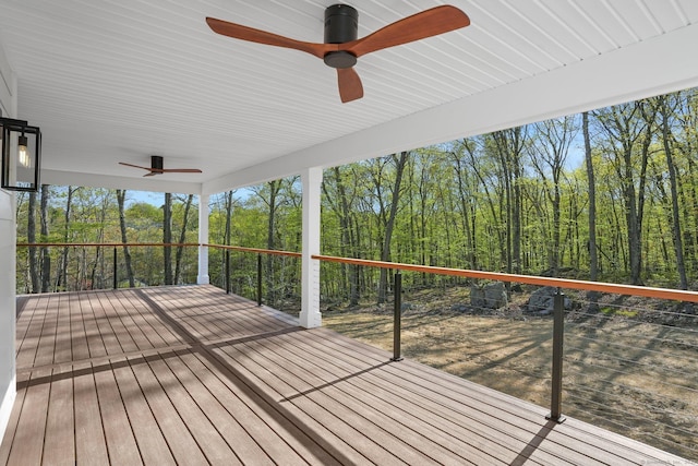 wooden deck with a ceiling fan and a wooded view