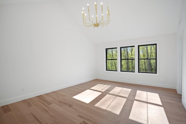 unfurnished room with high vaulted ceiling, baseboards, wood finished floors, and a chandelier