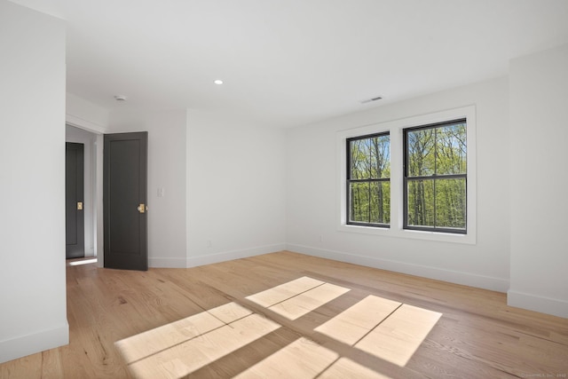 empty room with baseboards, light wood-style flooring, and visible vents