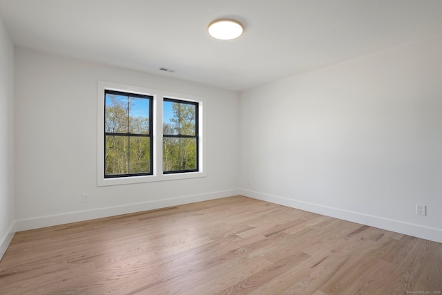 spare room featuring baseboards and light wood-style floors