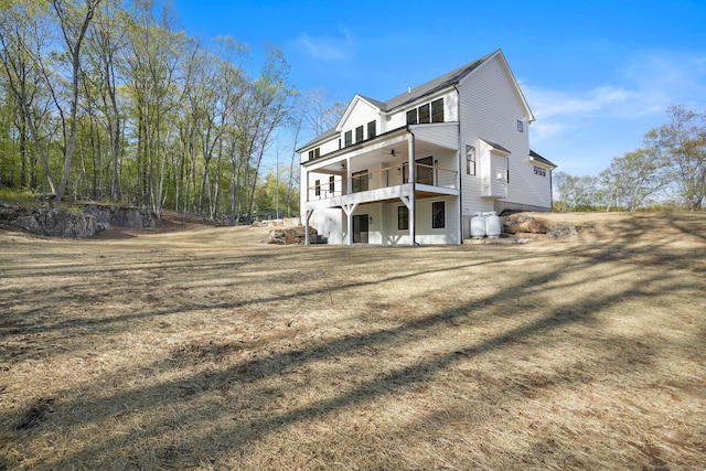 rear view of house featuring a ceiling fan and a balcony