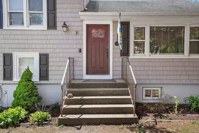 view of exterior entry with a shingled roof