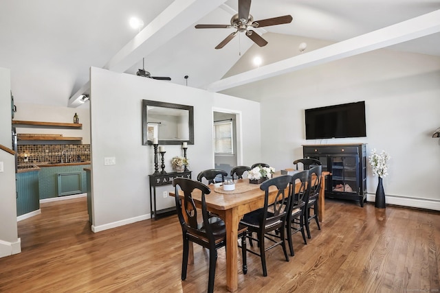 dining area featuring wood finished floors, beamed ceiling, baseboard heating, high vaulted ceiling, and a ceiling fan